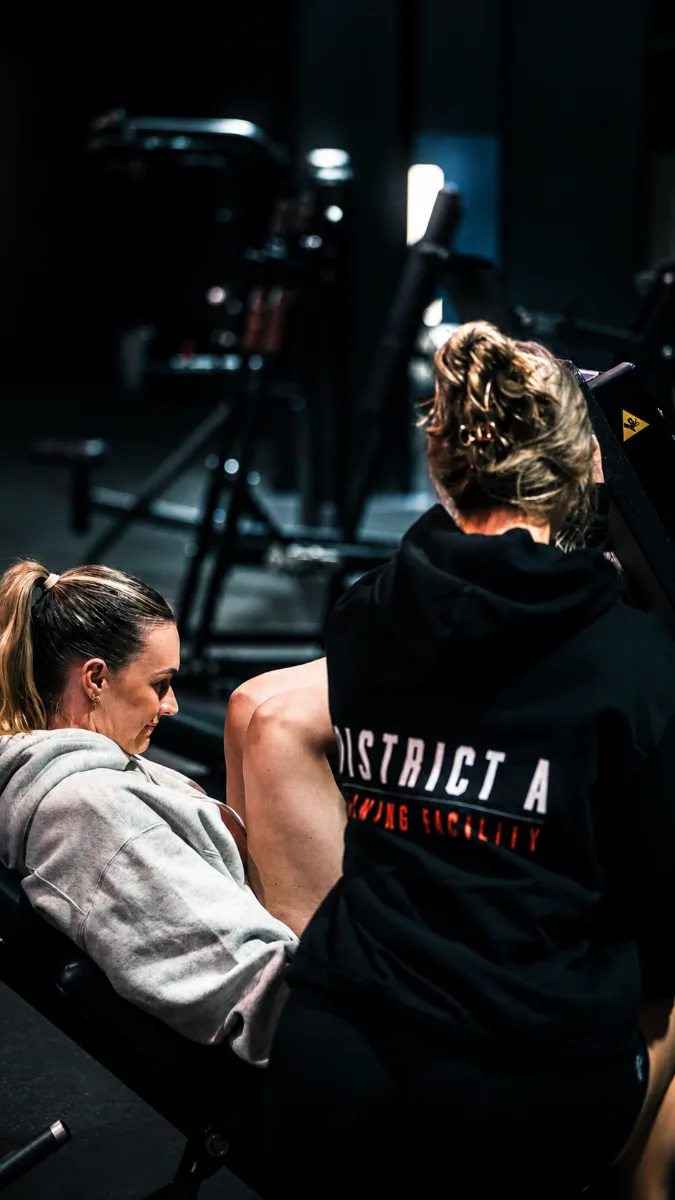 District A team member helping a member on the leg press